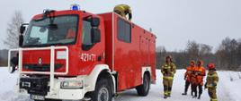 Na zdjęciu samochód ratownictwa wodnego. Obok stoją strażacy PSP w ubraniach typu nomex oraz ubraniach do ratownictwa lodowego.