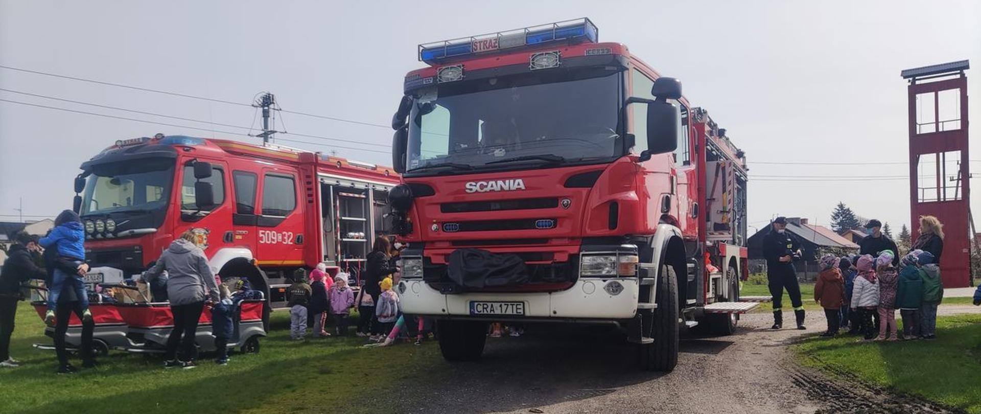 Zdjęcie przedstawia strażaków prezentujących dzieciom samochody gaśnicze JRG PSP Radziejów i Ochotniczej Straży Pożarnej w Osięcinach