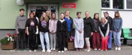 Grupa uczniów stojących na tle budynku internatu w opaskach z kocimi uszami na głowach