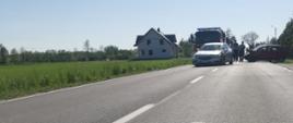 Droga Wojewódzka 982 w oddali widać dwa pojazdy biorące udział w kolizji, jeden stoi w poprzek drogi, za nimi pojazdy strażackie OSP
