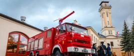 Plac wewnętrzny JRG 5, czerwony samochód gaśniczy, w tle wieża Centrum Edukacji i Historii Warszawskiej Straży Pożarnej