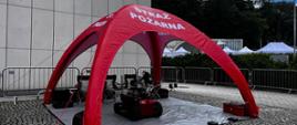 Namiot straży pożarnej. Pod nim strażacy prezentujący sprzęt, a mianowicie robota gaśniczego.