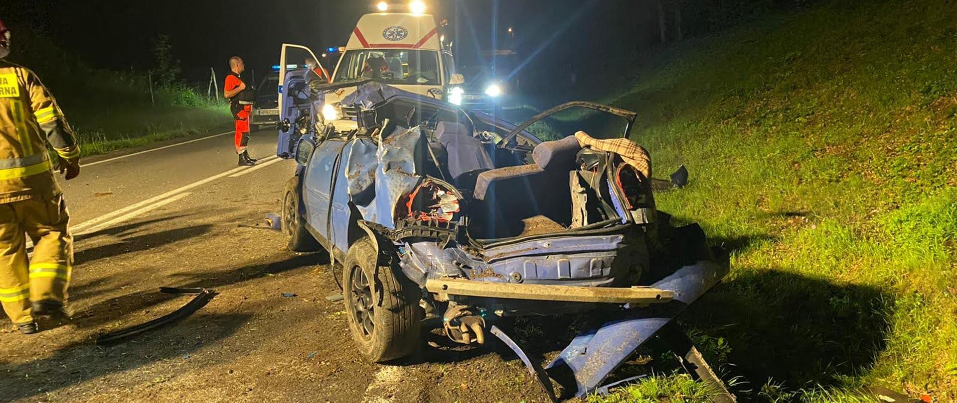 Rozbity samochód osobowy. W tle karetka pogotowia.