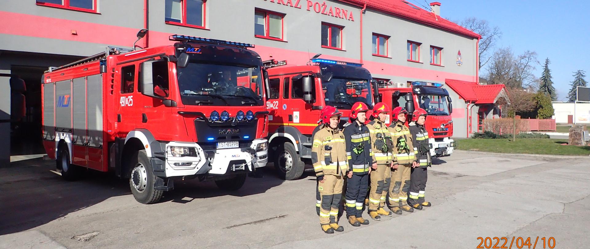 Starachowiccy strażacy oddalający hołd Ofiarom Katastrofy Smoleńskiej, w tle pojazdy pożarnicze z włączonymi sygnałami świetlnymi