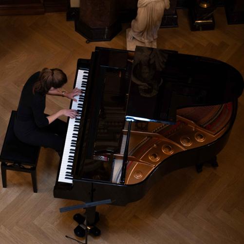 zdjęcie przedstawia laureatkę stypendium wykonującą utwór na fortepianie, zdjęcie z boku z góry