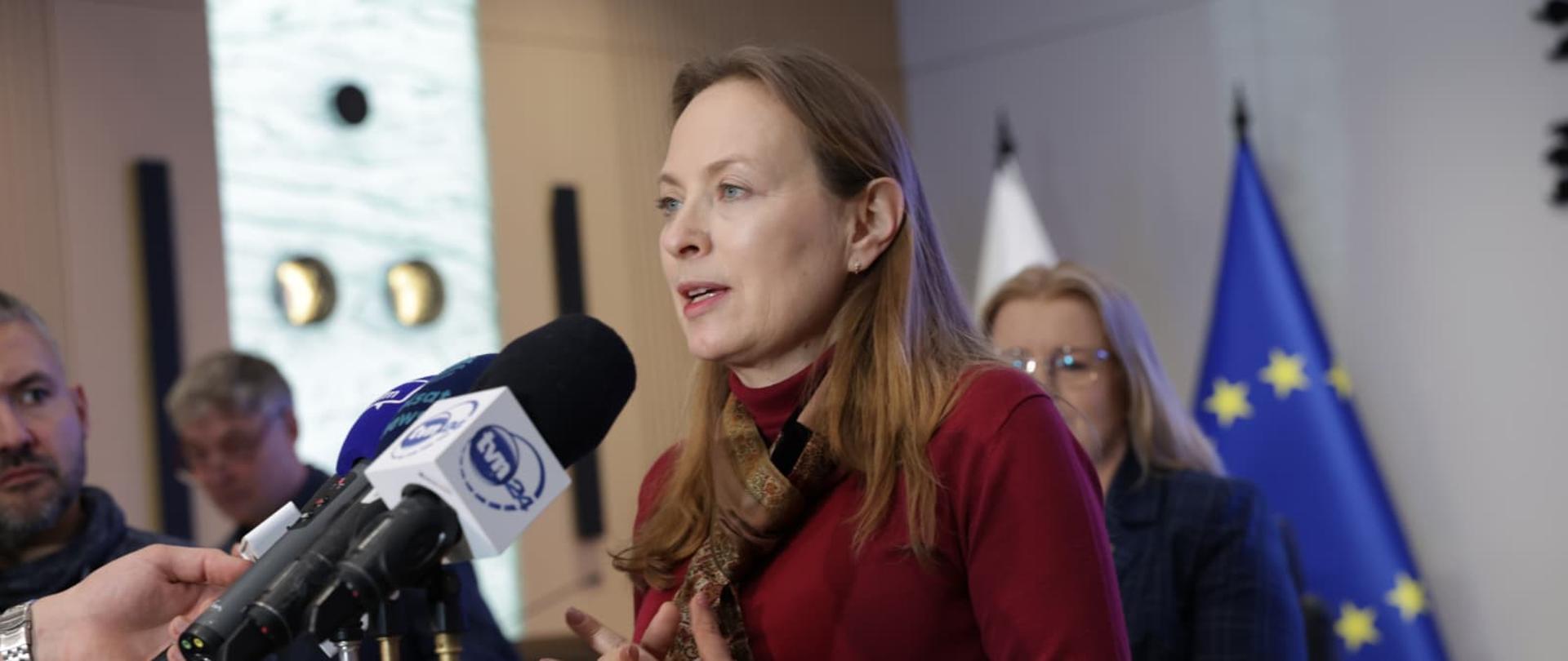 Na zdjęciu Minister Katarzyna Pełczyńska-Nałęcz przed mikrofonami odpowiada na pytania dziennikarzy