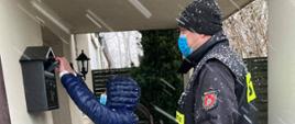 Strażak wraz z druhem MDP wkłada ulotki do skrzynki