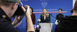 Na zdjęciu minister Katarzyna Pełczyńska-Nałęcz przed mikrofonami odpowiada na pytania dziennikarzy