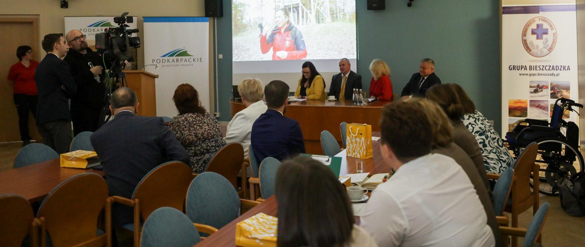 W sali konferencyjnej siedzą osoby. Wśród nich wiceminister Małgorzata Jarosińska-Jedynak na tle ekranu.