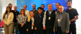 Uczestnicy warsztatu Workshop PSAR Review Warsaw 2025 stoją na tle ścianki z logiem Państwowej Agencji Atomistyki