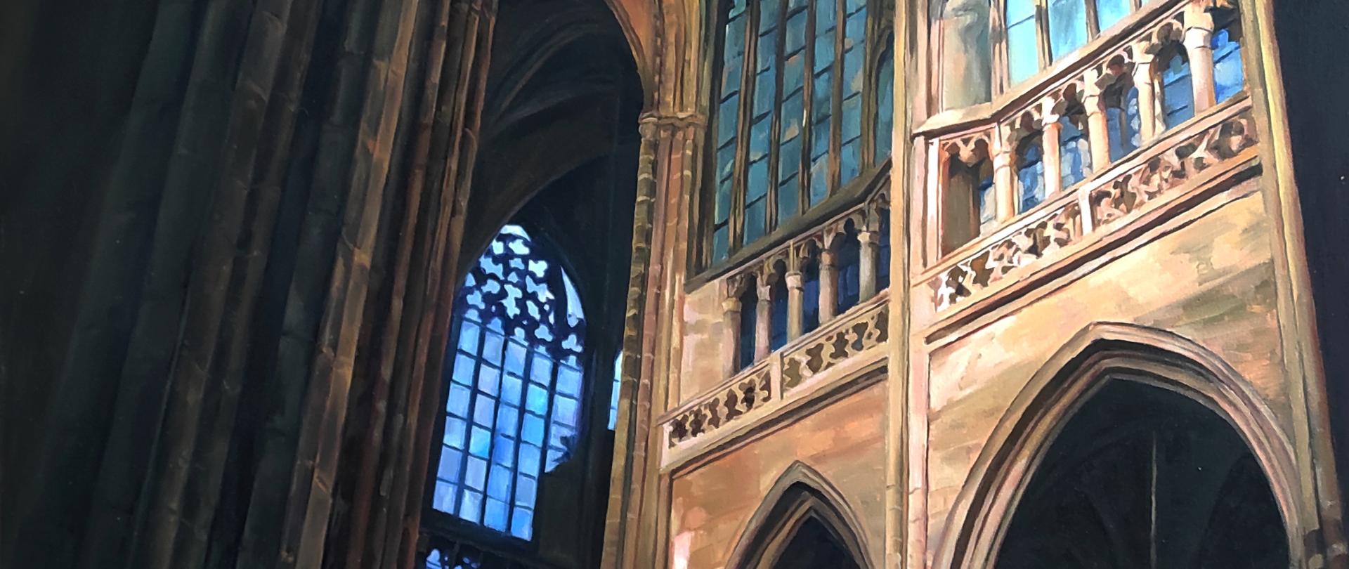 Wnętrze gotyckiej katedry z wysokimi ostrołukowymi arkadami i dużymi oknami wypełnionymi niebieskim światłem. Po prawej stronie widoczne są dekoracyjne galerie i smukłe kolumny, a po lewej masywne filary pogrążone w cieniu. Ciepłe światło słoneczne oświetla fragmenty kamiennych ścian, tworząc kontrast z chłodnym błękitem witraży i ciemnym wnętrzem świątyni.