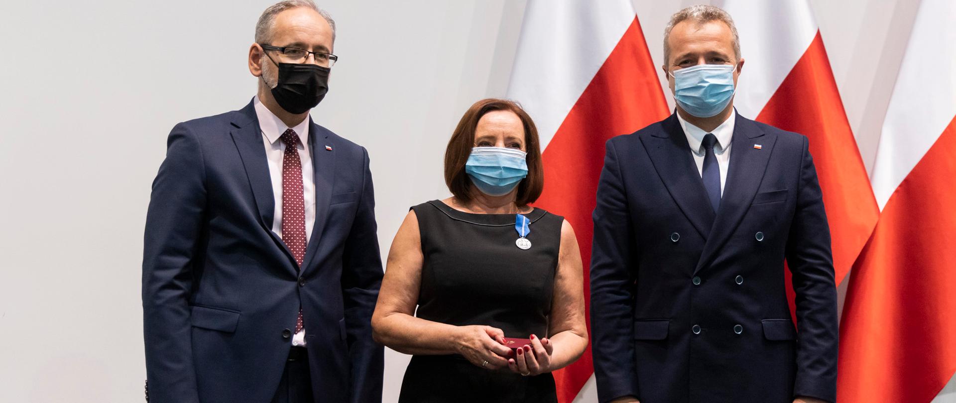 Jubileuszu 40-lecia Szpitala Uniwersyteckiego nr 2 im. dr. Jana Biziela. Trzy osoby stoją na tle flag. 