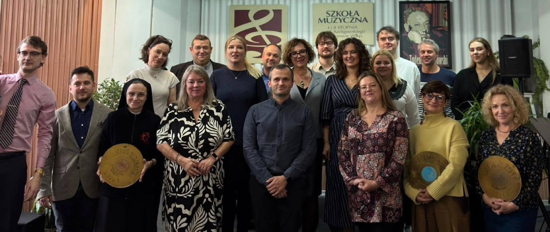 Nauczyciele szkoły w auli stojący przed sceną