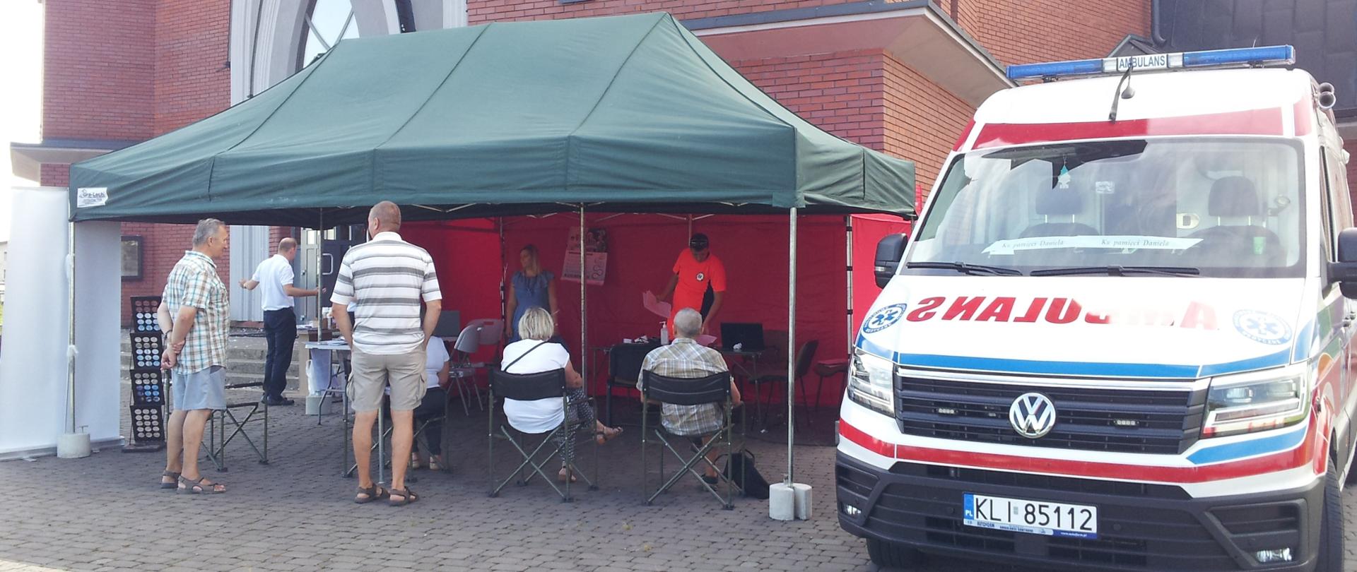Namiot pod którym czekają ludzie na przyjęcie szczepionki. Z prawej karetka pogotowia.