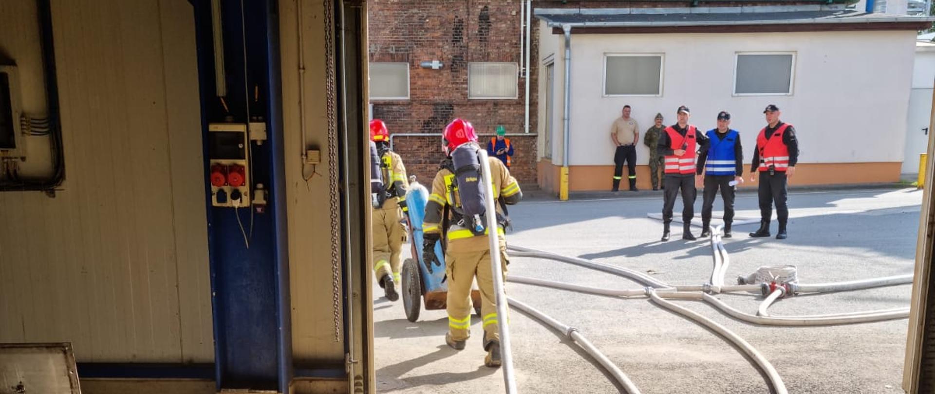 Fotografia przedstawia wykonywanie ćwiczenia bojowego przez strażaków jednostki ratowniczo - gaśniczej w Malborku na terenie zakładu Cukrowni Malbork.