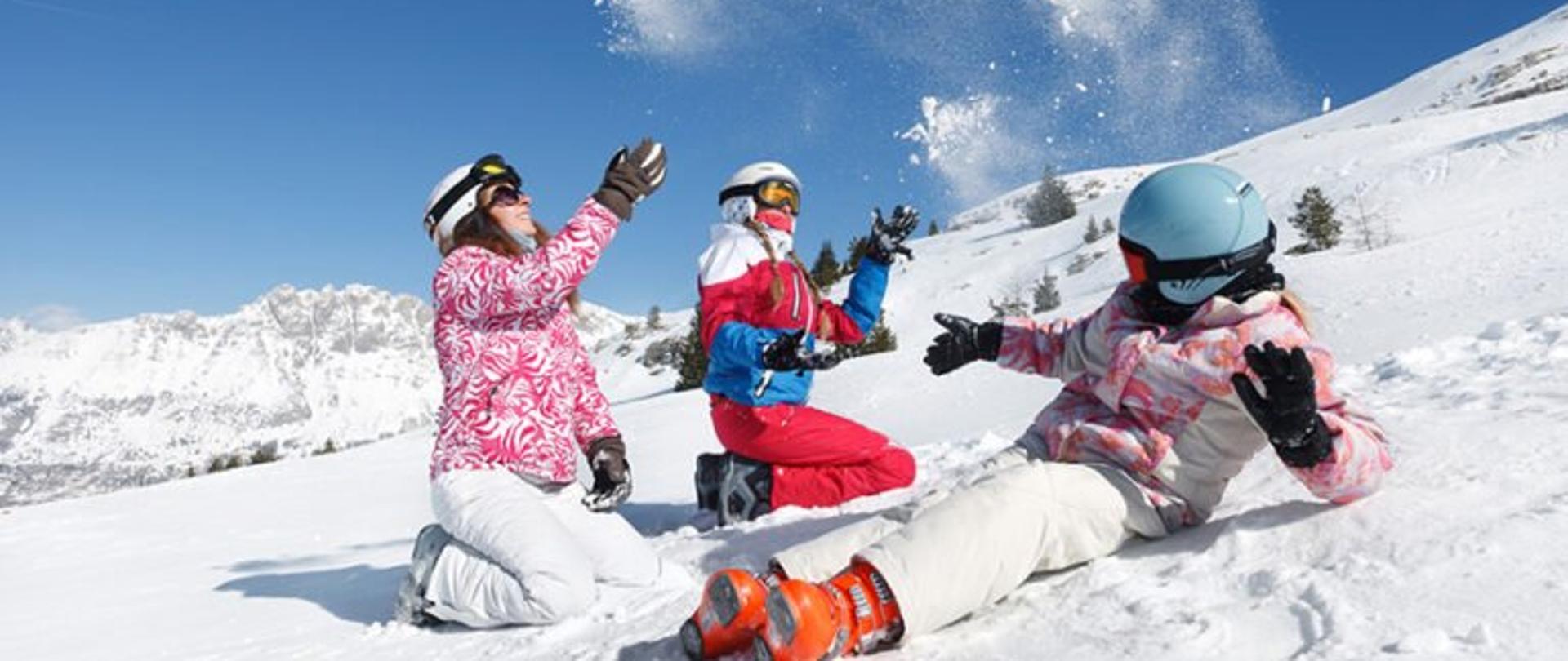 Trzy osoby w strojach narciarskich na stoku