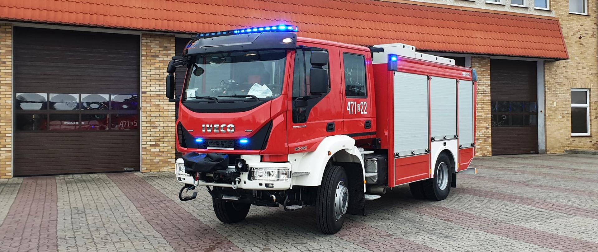 Samochód gaśniczy z zamkniętymii skrytkami, na tle bram garażowych