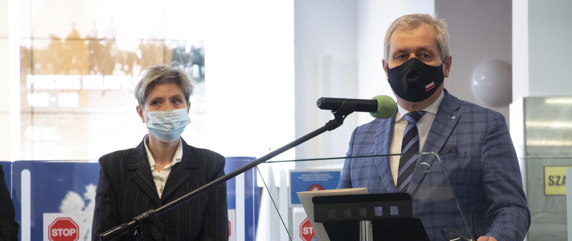 Na zdjęciu przemawiający zza mikrofonu wojewoda opolski, stojący na tle dużego ekranu. Obok p.o. IPN w Opolu 