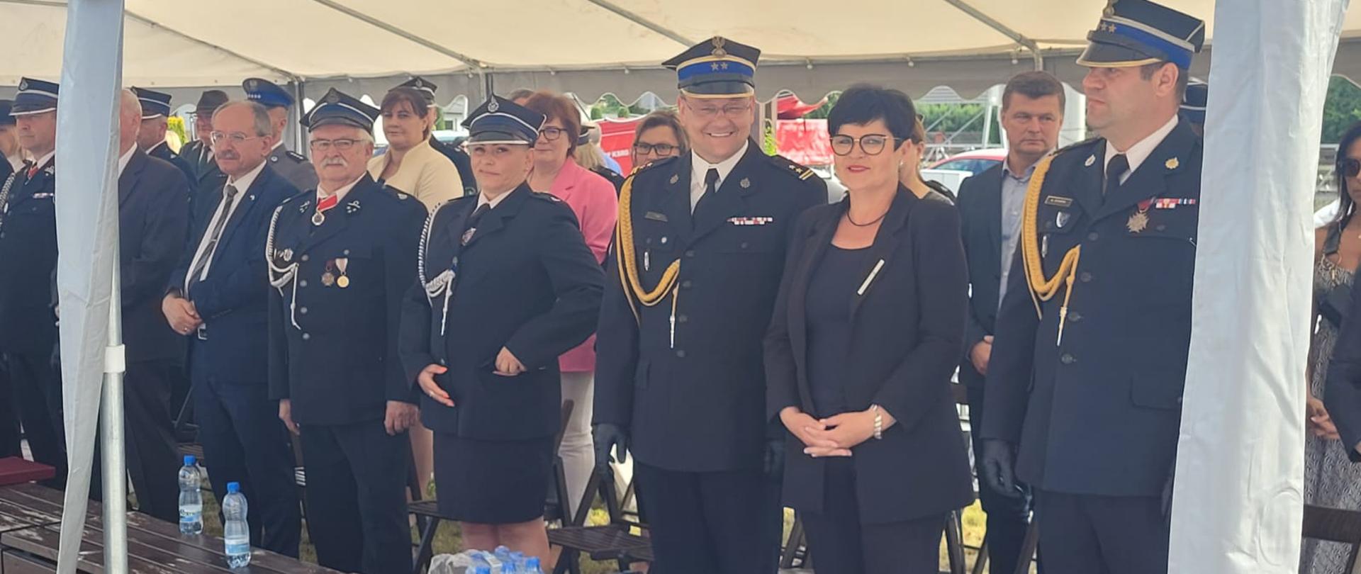 Zastępca Komendanta Centralnej Szkoły PSP w towarzystwie Pani poseł oraz innych gości stojący podczas uroczystości