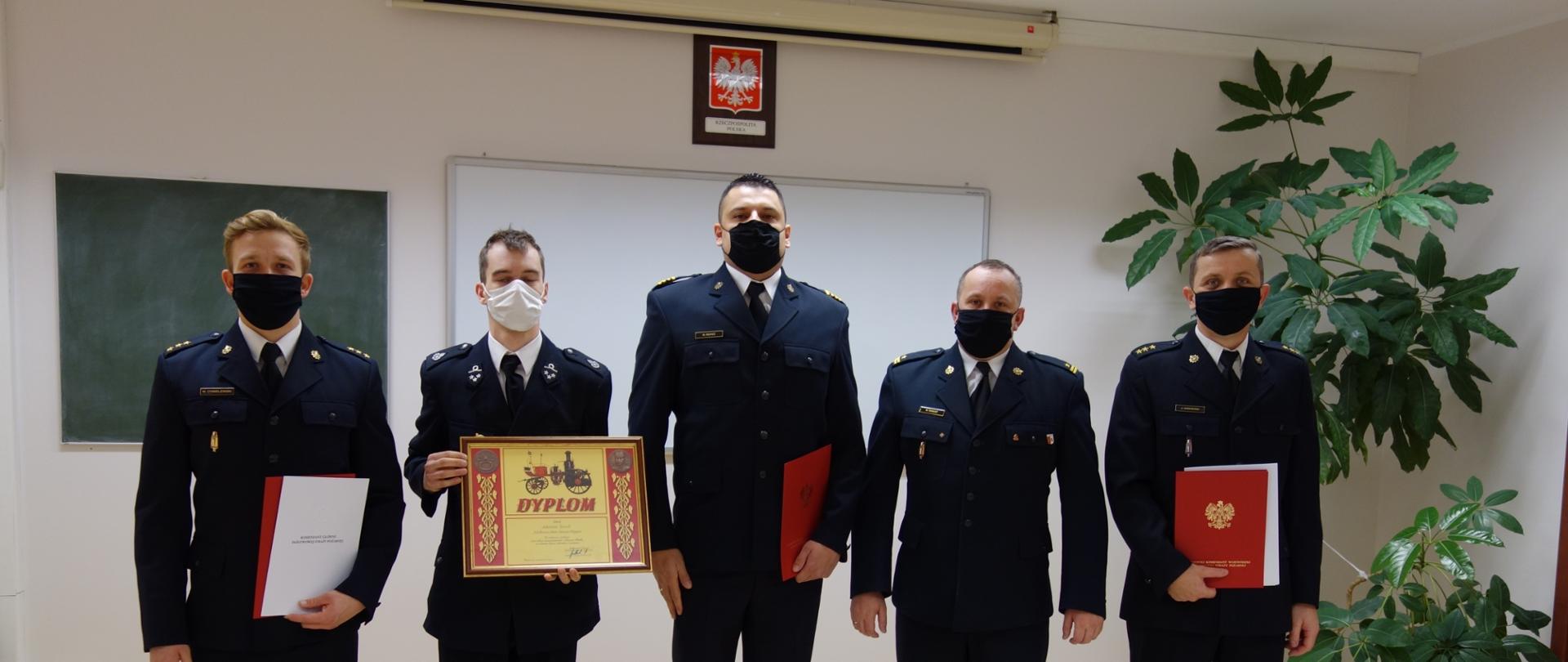 Funkcjonariusze KP PSP w Pruszczu Gdańskim oraz dh Arkadiusz Żeźnik prezentują wyróżnienia z okazji Narodowego Święta Niepodległości. Zdjęcie zrobione w sali tut. Komendy. 