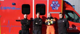 1. Mistrzostwa Pierwszej Pomocy - 4 strażacy biorący udział w wydarzeniu na tle samochodu