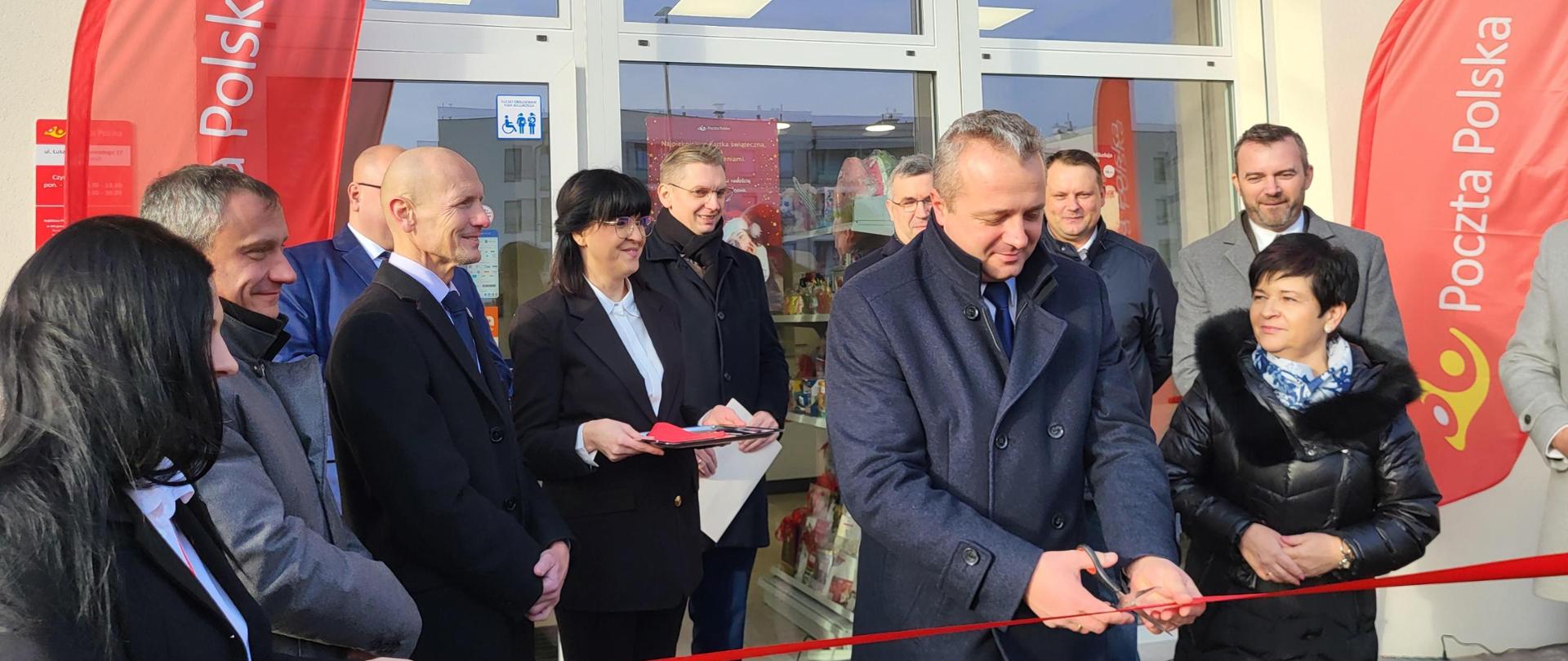 Wojewoda Mikołaj Bogdanowicz przecinający wstęgę z okazji otwarcia nowego punktu Poczty Polskiej S.A. w Toruniu 