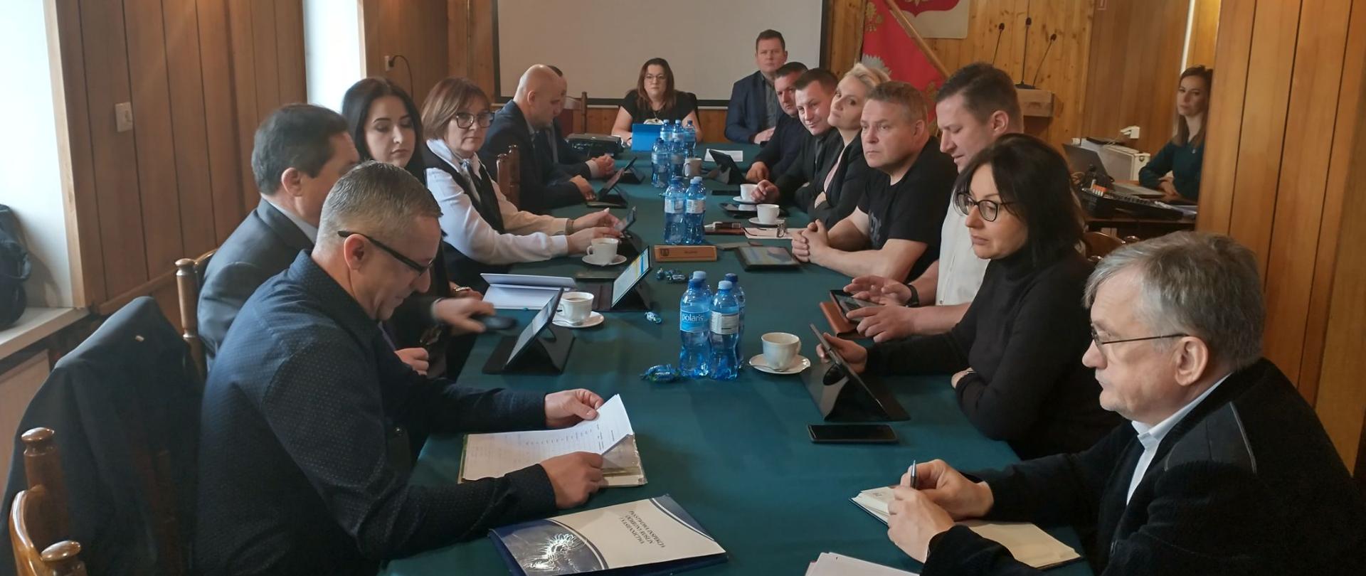 Uczestnicy spotkania siedzą przy stole konferencyjnym