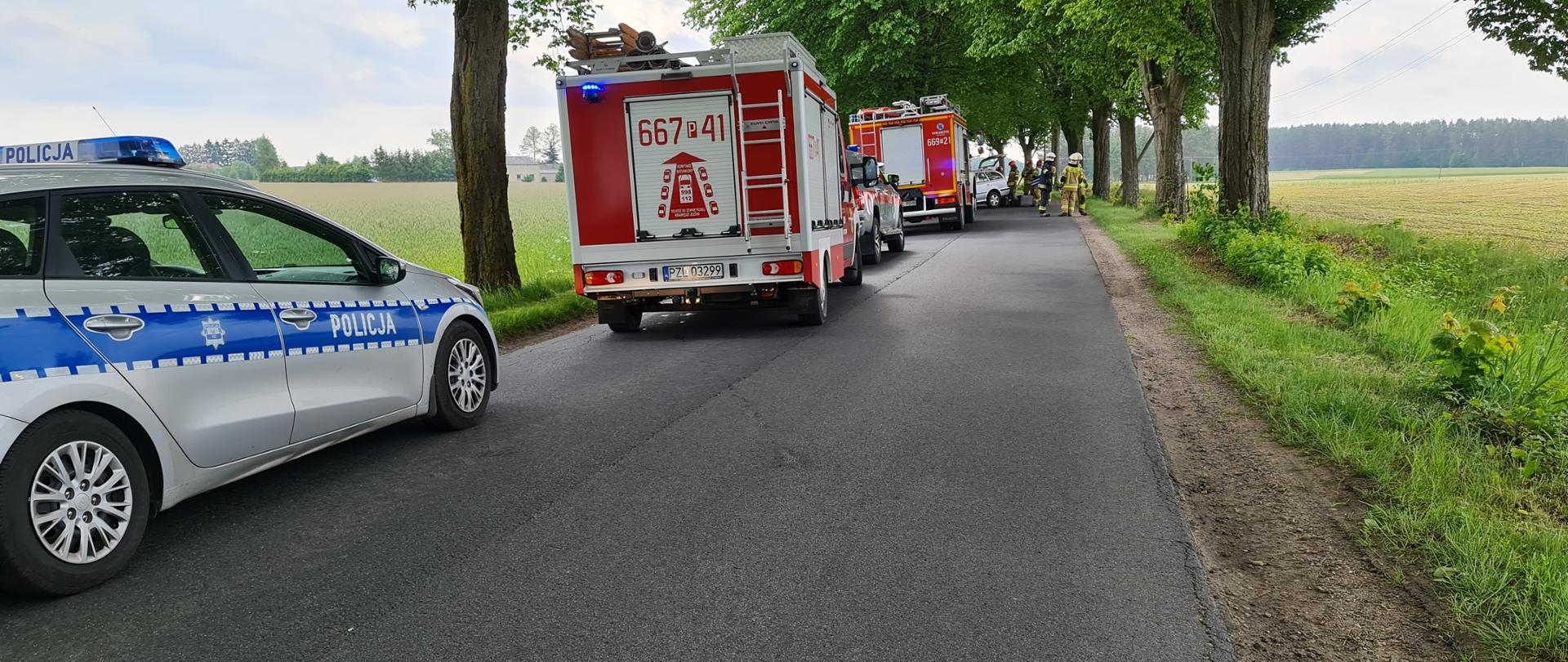 Na Zdjęciu widoczne są samochody strażackie drzewa samochód policji droga asfaltowa strażacy przy samochodzie.