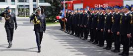 Mazowiecki Komendant Wojewódzki Państwowej Straży Pożarnej dokonuję przeglądu pododdziałów Państwowej i Ochotniczych Straży Pożarnych oraz Pocztów Sztandarowych stojących przed Budynkiem KP PSP Mińsk Mazowiecki, oddaje honor idąc wzdłuż pododdziałów
