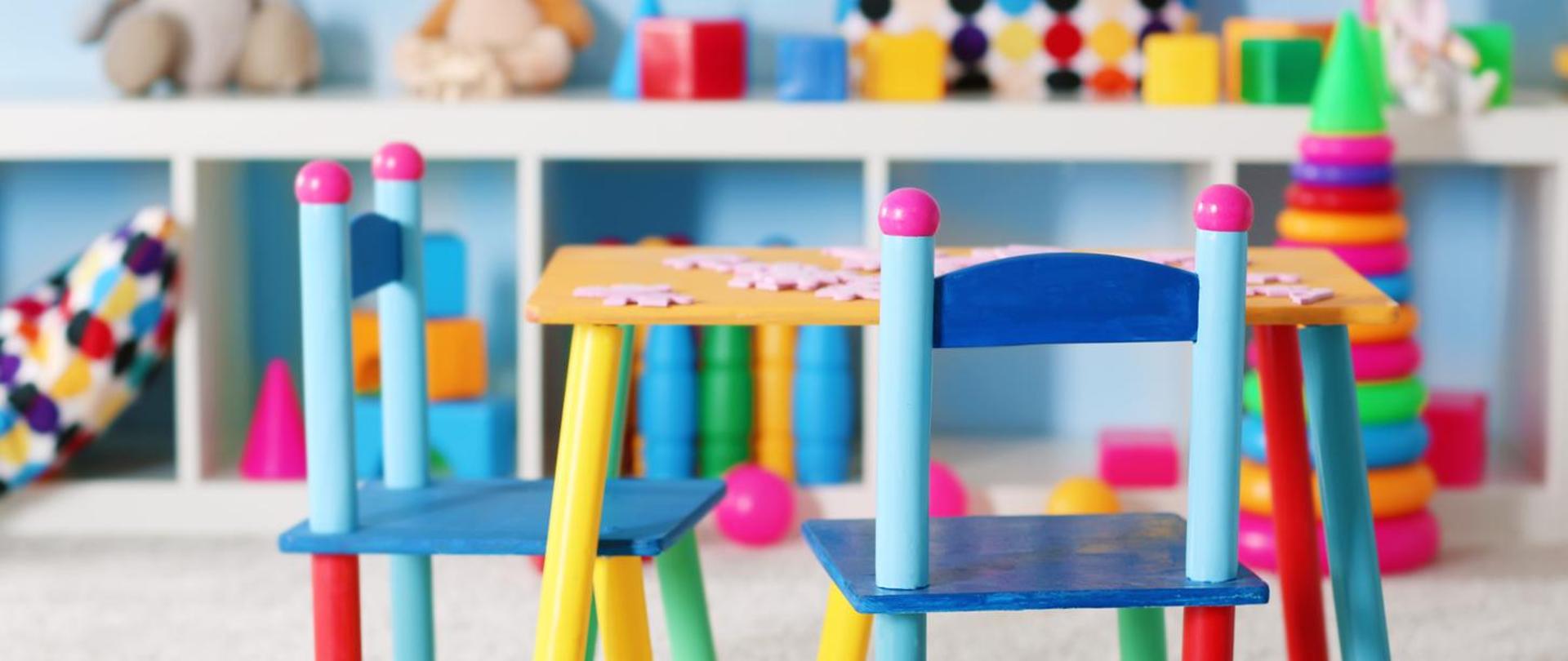 Na zdjęciu znajdują się kolorowe krzesła i stolik