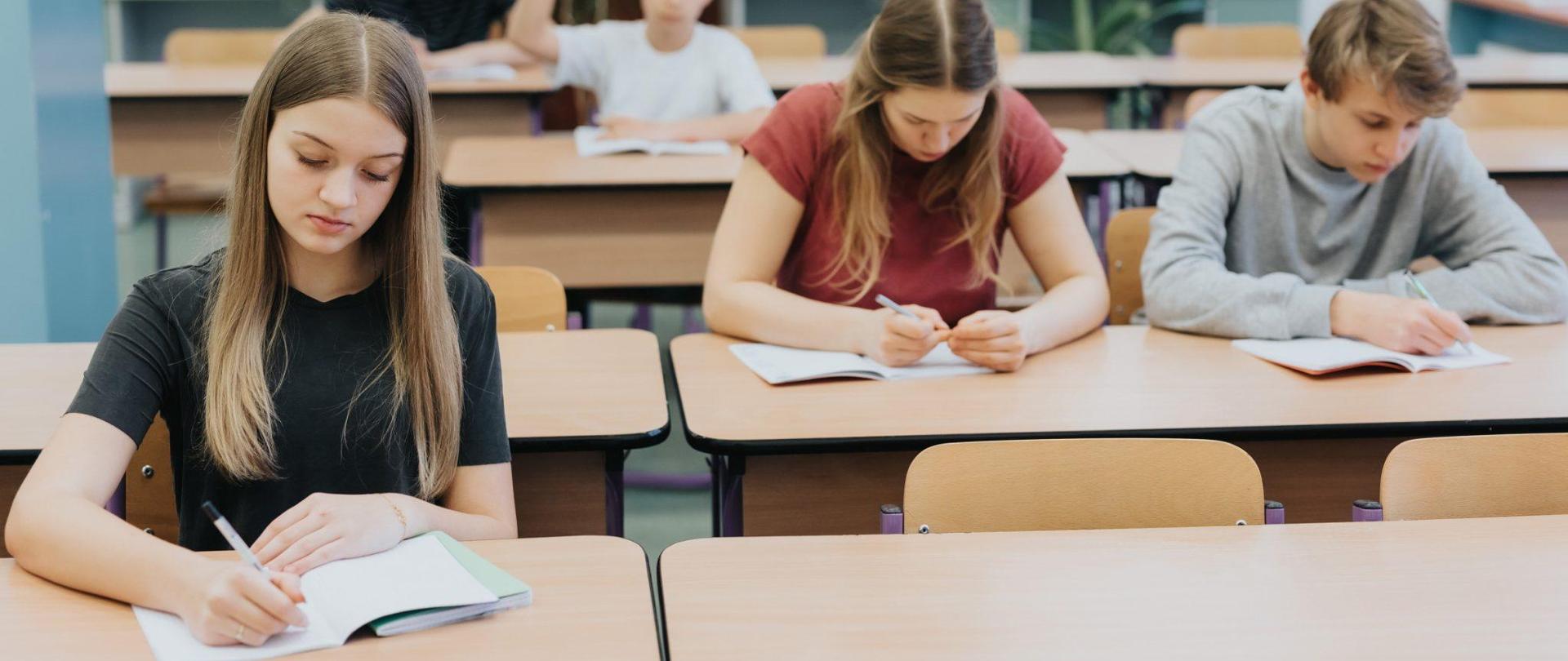 zdjęcie przedstawia uczniów siedzących w ławkach szkolnych
