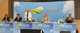 Widok na stół prezydialny - wicewojewoda i eksperci siedzą przy stole, dyrektor generalna KOWR stoi i przemawia