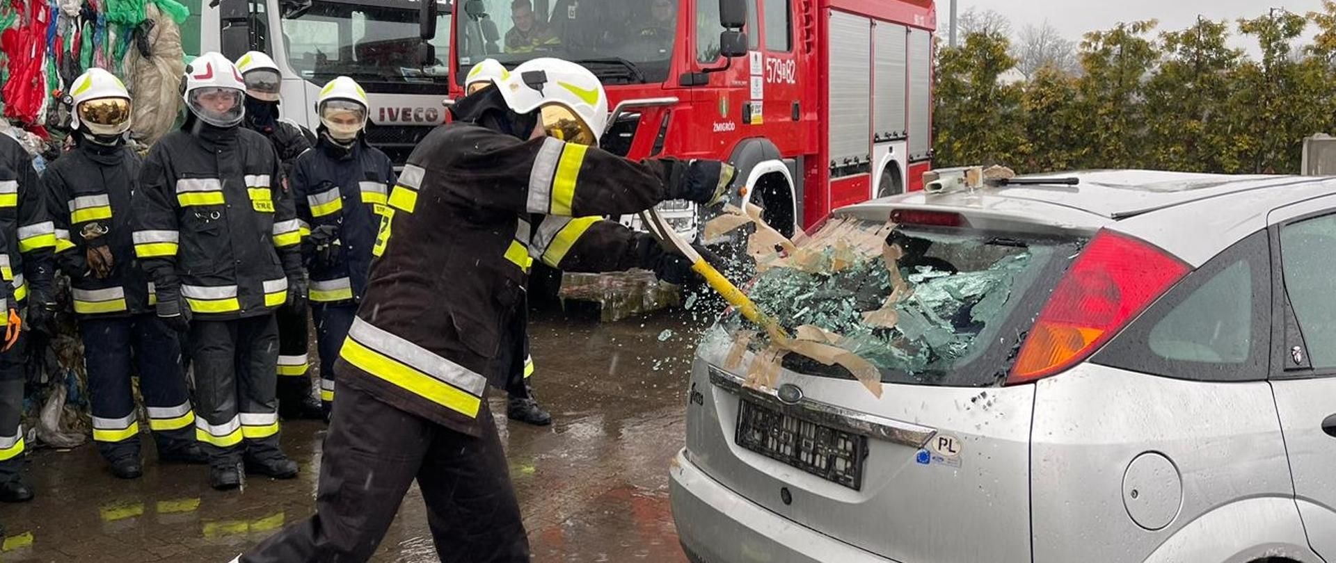 Strażak wybijający szybę w aucie