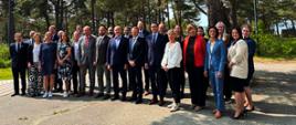 Zdjęcie grupowe uczestników Posiedzenia Dyrektorów Generalnych Ochrony Ludności RPMB w plenerze – delegaci z państw Morza Bałtyckiego na tle drzew w Laulasmaa.