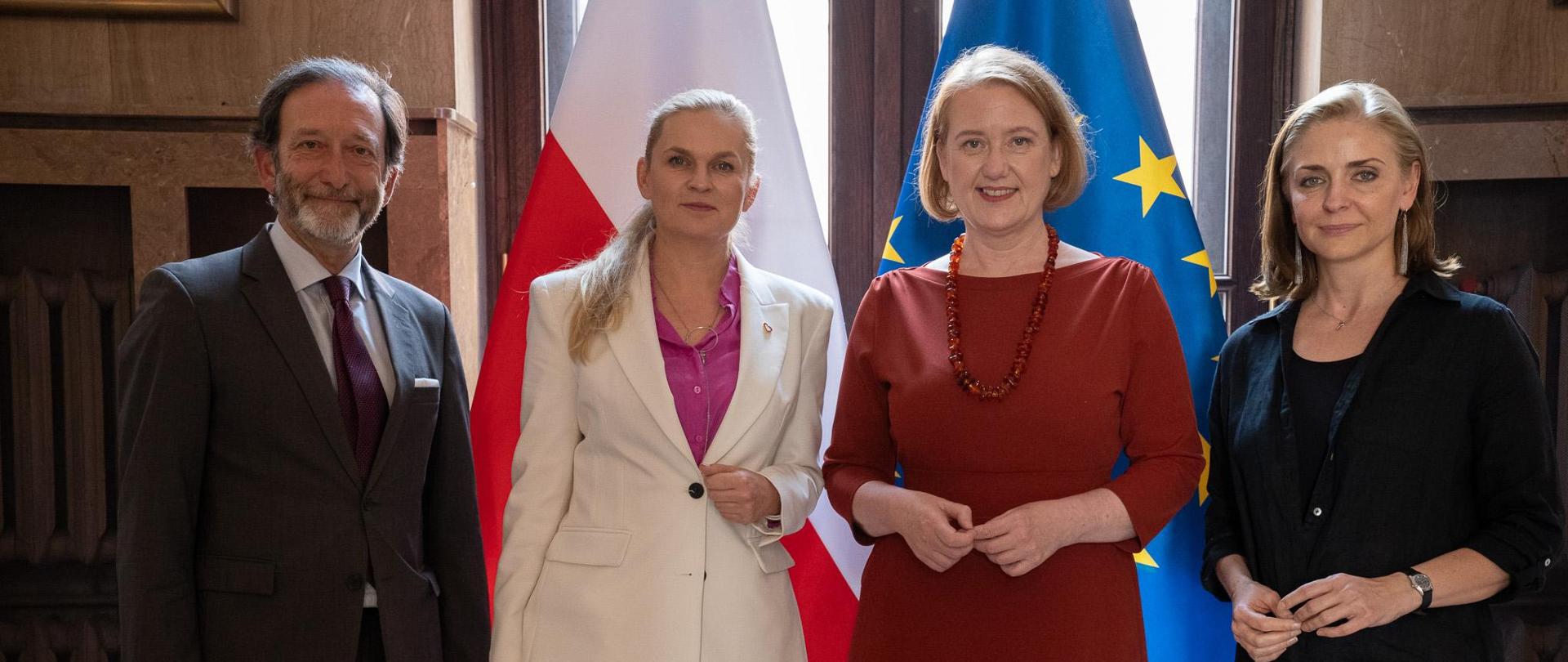 Zdjęcie zbiorowe. Na tle flag Polski i EU stoi Minister Nowacka i Wiceminister Mucha oraz mężczyzna i kobieta z niemieckiej delegacji. 