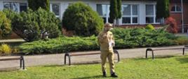 Funkcjonariusz PSP podczas omawiania przebiegu ewakuacji oraz pogadanki dla uczniów i kadry szkoły podstawowej.