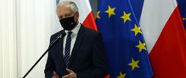 Wicepremier, minister rozwoju, pracy i technologii Jarosław Gowin stojący przy mównicy, za jego plecami flagi Polski i UE