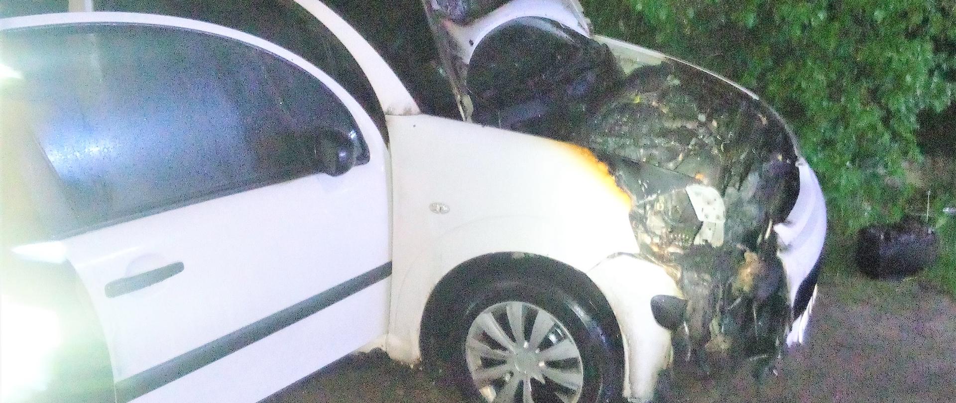 Zdjęcie przedstawia samochód osobowy biały Citroen C3 zniszczony przez ogień. 