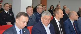 W świetlicy komendy powiatowej PSP w Rawiczu siedzą uczestnicy narady - przedstawiciele władz samorządowych, służb mundurowych oraz funkcjonariusze i funkcjonariuszki komendy. Strażacy oraz przedstawiciele zaprzyjaźnionych służb występują w umundurowaniu wyjściowym i koszarowym. 