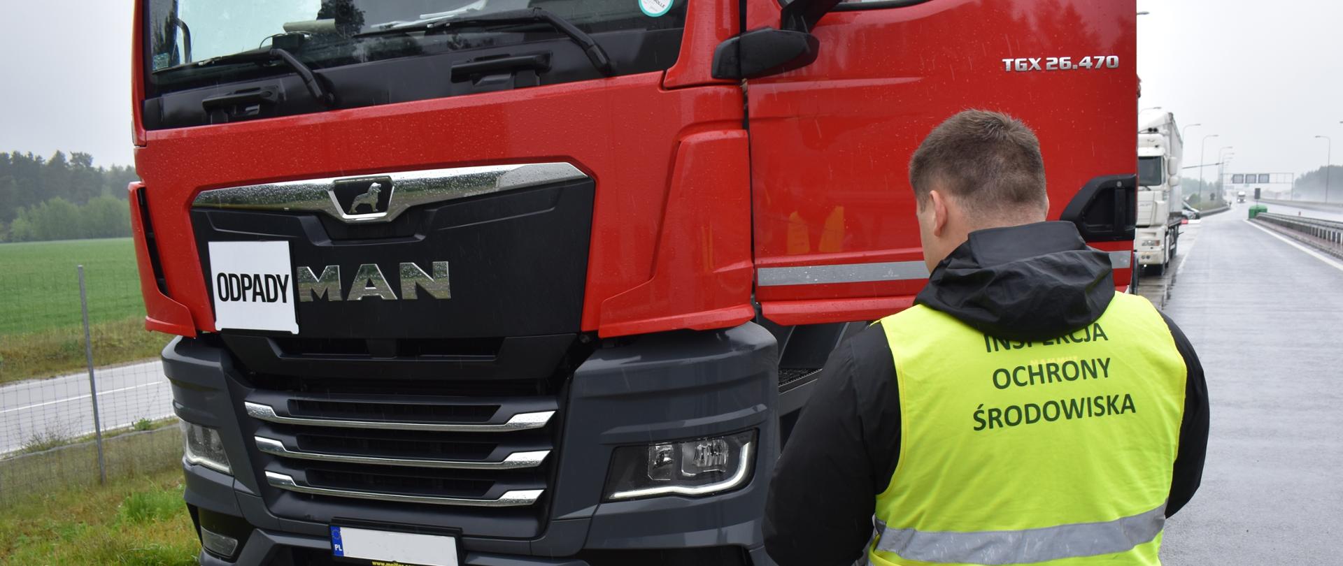 Inspektor Wojewódzkiego Inspektoratu Ochrony Środowiska w Warszawie kontroluje samochód ciężarowy.