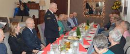 Świąteczne spotkanie strażackich emerytów. Sala w jednej z rawickich restauracji. Po obu stronach stołu zasiadają uczestnicy spotkania, mężczyźni i kobiety. Na stole są białe filiżanki, szklanki, talerzyki, sztućce i dzbanki oraz czerwone serwetki, surówki i ciasto. Przy stole stoi mężczyzna w mundurze strażackim, który przemawia do zebranych.