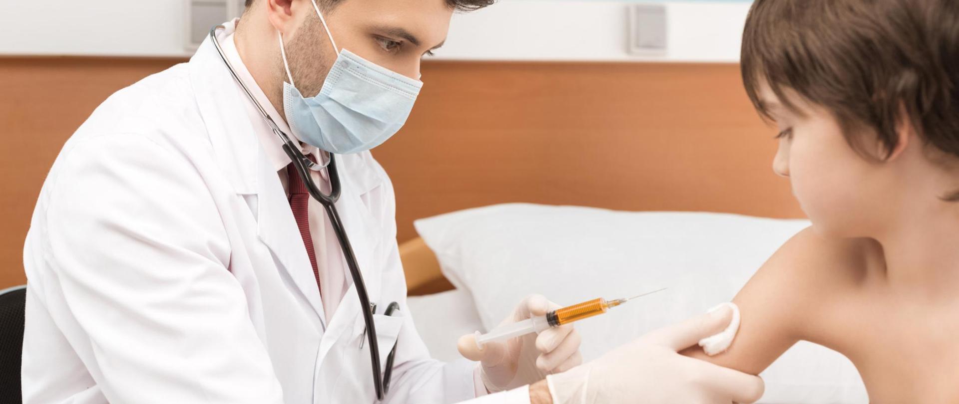 Na zdjęciu widać lekarza, który szczepi chłopca.