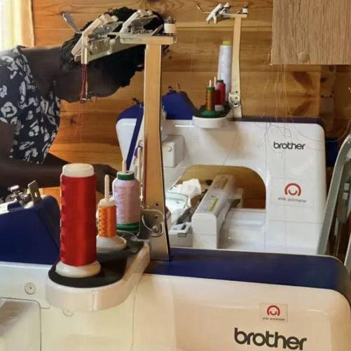 Młoda szwaczka przy maszynach do szycia z logo Polskiej pomocy