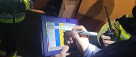 Zdjęcie przedstawia strażaka zapisującego pomiary na tablicy zarządzania powietrzem 