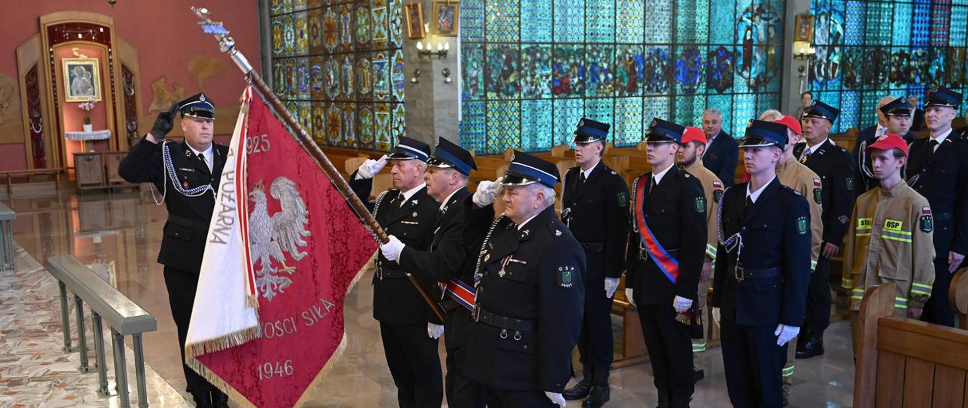 Na zdjęciu kilku strażaków OSP w mundurach galowych ze sztandarem. Stoją w kościele. 
