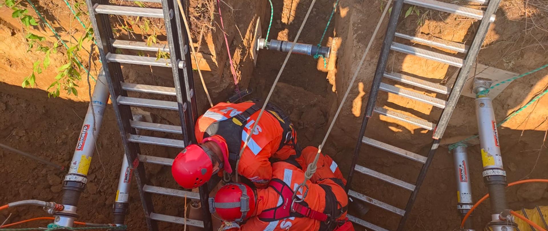 Ratownicy udzielają pomocy osobie zasypanej w wykopie w kształcie litery T