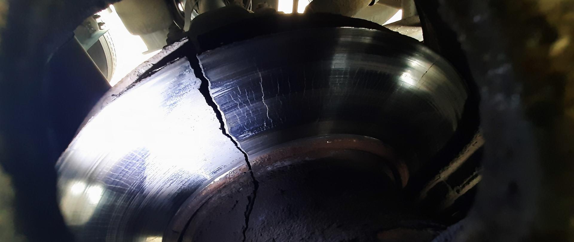 Pęknięta na całej szerokości roboczej tarcza hamulcowa przy kole na drugiej (środkowej) osi ukraińskiej naczepy.