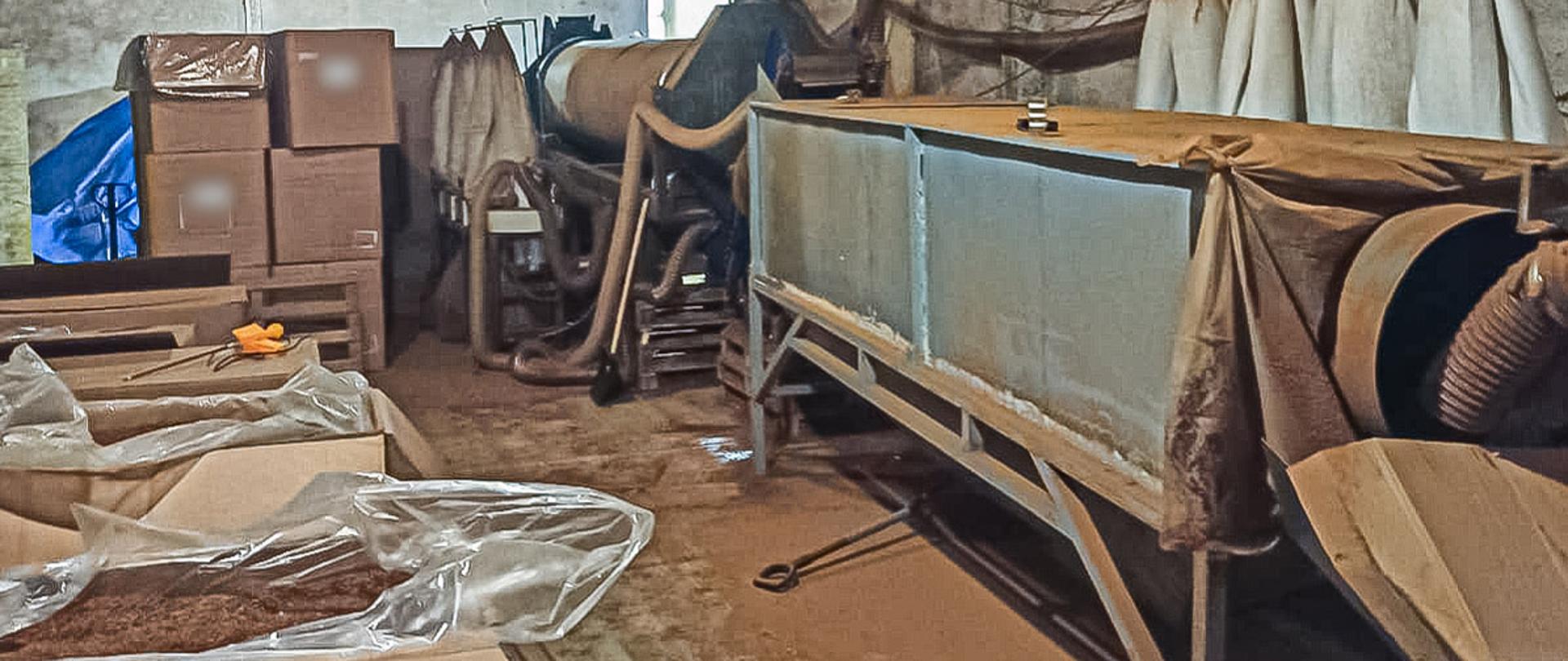 Pomieszczenie z tytoniem w kartonach i maszynami do produkcji tytoniu.