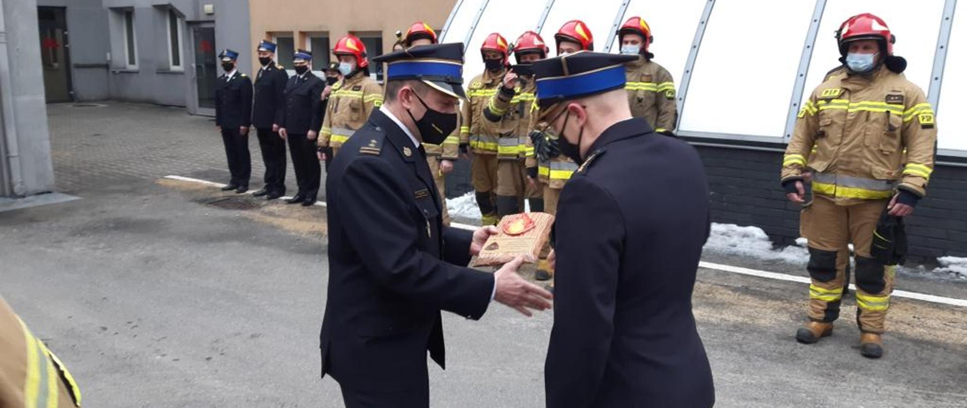 Zdjęcie przedstawia Komendanta Miejskiego Państwowej Straży Pożarnej dziękującemu funkcjonariuszowi przechodzącemu na zaopatrzenie emerytalne