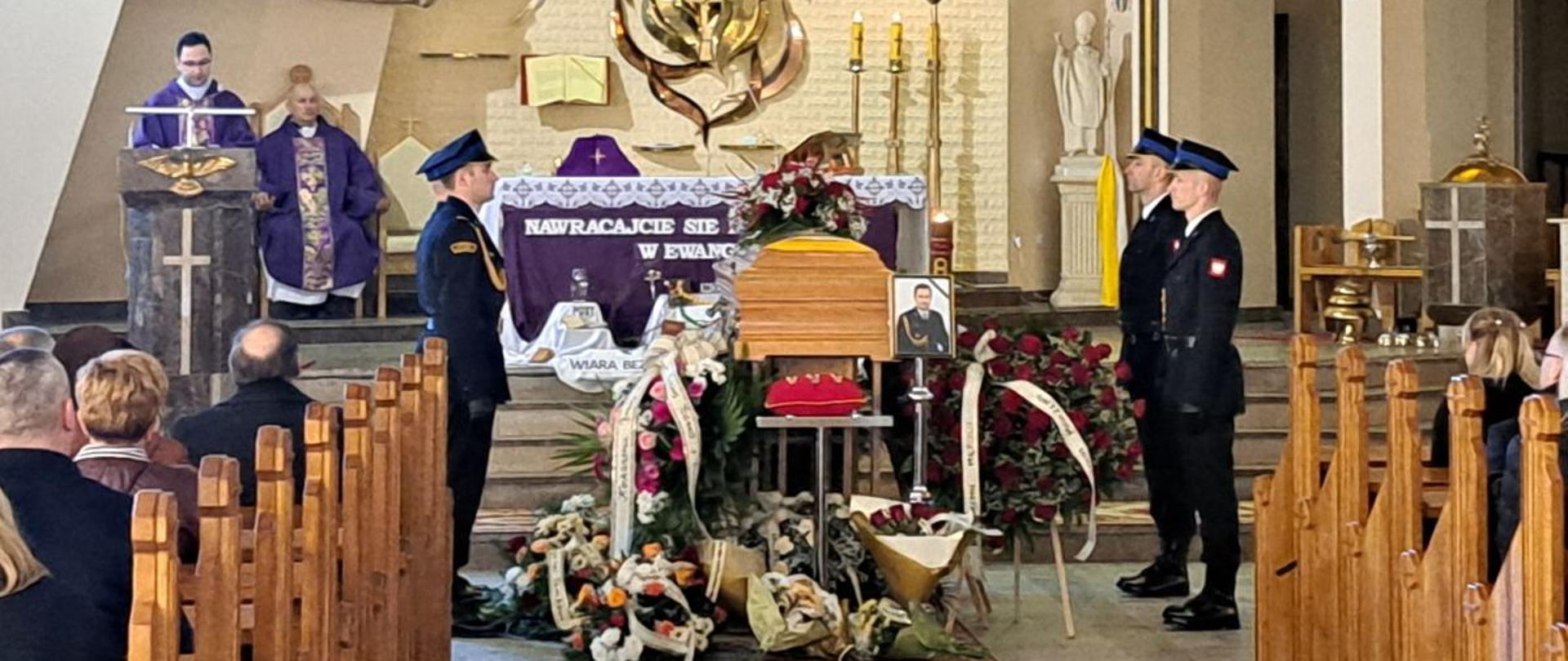 Zdjęcie przedstawia pogrzeb śp. Tomasza Karepina. W kościele przy trumnie zmarłego asystują strażacy. Księża stoją przy ołtarzu. Ludzie siedzą w ławkach. 